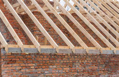 İnşaatta ahşap kirişlerin yerleştirilmesi tuğla evin çatı kiriş sistemi. Mauerlat monolitik çerçevede yatıyor.