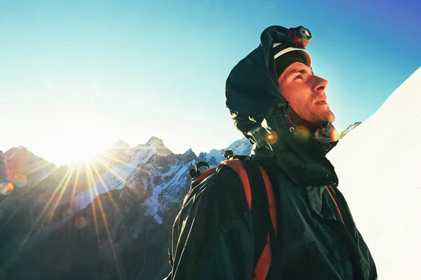 Bergbeklimmer bereikt de top van een besneeuwde berg — Stockfoto