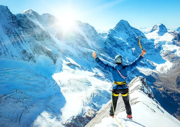 Mountaineer atinge o topo de uma montanha nevada. Conceito de desporto extremo — Fotografia de Stock