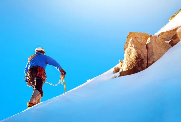 Ορειβάτης φτάνει στην κορυφή του ένα χιονισμένο βουνό — Φωτογραφία Αρχείου