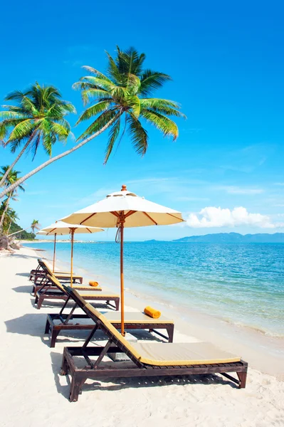 Пляжные стулья на белом песчаном пляже с облачным голубым небом — стоковое фото
