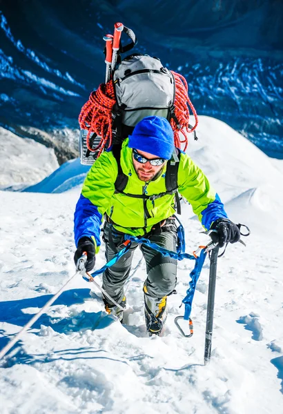 L'alpiniste atteint le sommet d'une montagne enneigée — Photo
