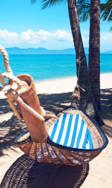 Kumsaldaki palmiye ağaçları arasında boş hamak.