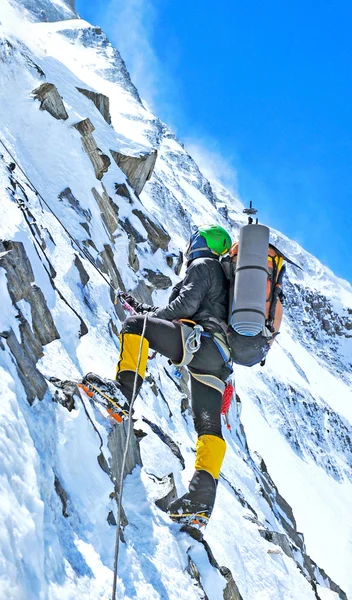 Bergbeklimmer bereikt de top van een besneeuwde berg — Stockfoto