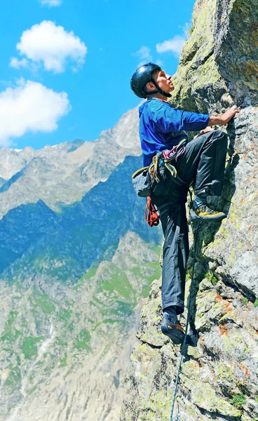 Jeune homme grimpe sur une paroi rocheuse — Photo