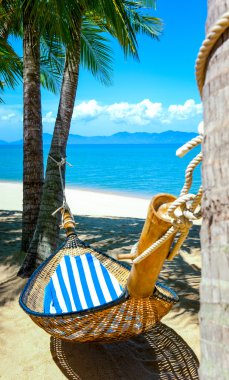 Kumsaldaki palmiye ağaçları arasında boş hamak.