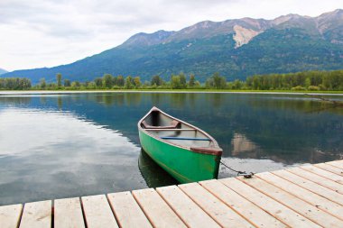 Arka planda dağlar olan bir rıhtıma bağlı bir kano.