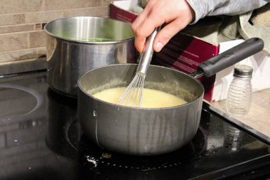 Kirli bir sobanın üzerinde bir perukla tencereyi karıştıran bir el.