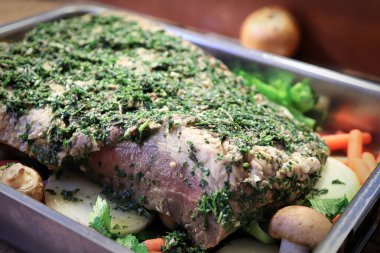 Tavada çiğ göğüs eti ve üzerinde bitkiler var.