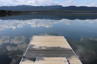 Bulutlar açık bir dağ gölünde yansıyor.