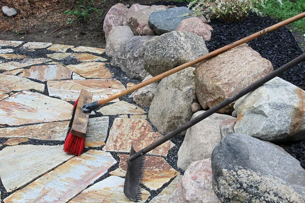 Un rastrello e una scopa usati sulle pietre del patio — Foto Stock