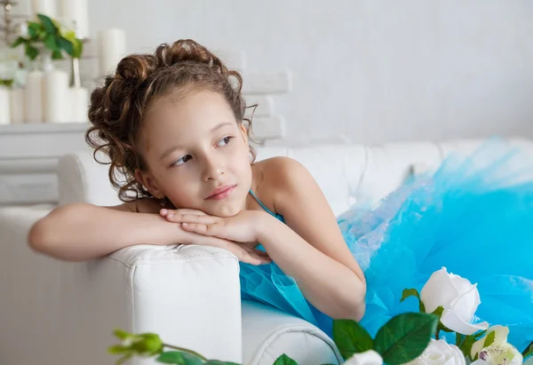 Маленька дівчинка в блакитній сукні лежить на дивані — стокове фото