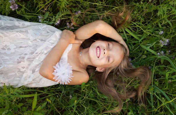 Menina em vestido branco deitado na grama e ri — Fotografia de Stock