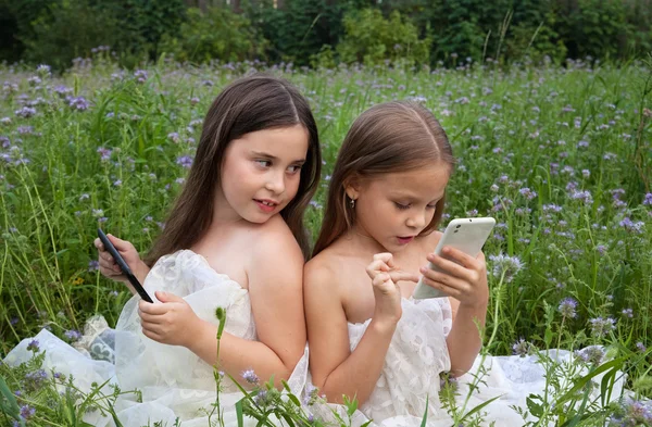 Dos chicas jugando en el teléfono y la tableta — Foto de Stock