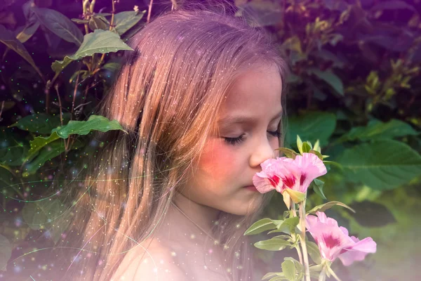 Pequena menina bonita cheirando uma flor — Fotografia de Stock