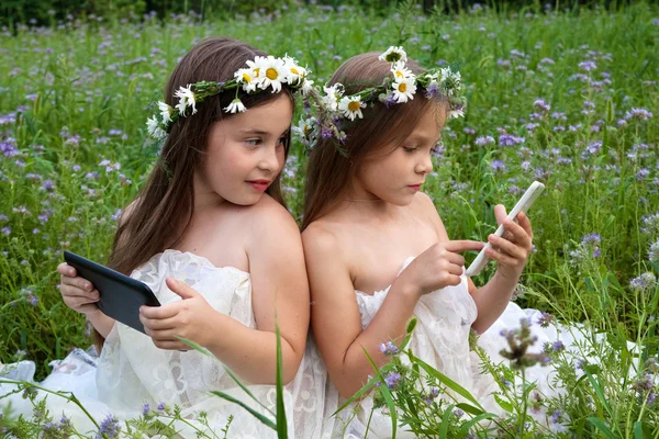 Dos chicas jugando en el teléfono y la tableta — Foto de Stock