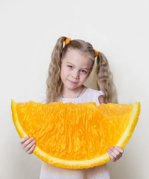 Menina com uma grande fatia de laranja em suas mãos, como um conceito para alcançar um melhor e mais na vida — Fotografia de Stock