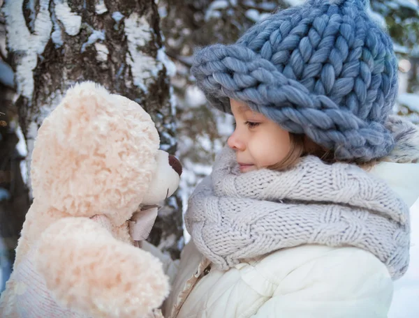 Menina com urso de pelúcia macio em um parque de inverno — Fotografia de Stock