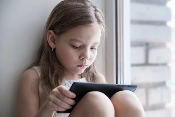 Küçük kız camda oturan tablet ile