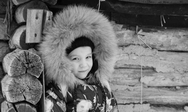 Flickan står i vintern nära det gamla trähuset — Stockfoto