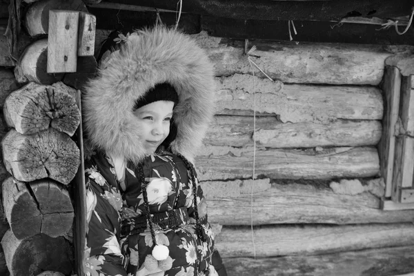 Chica de pie en el invierno cerca de la antigua casa de madera — Foto de Stock