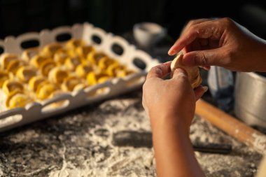 Kadın elleri mutfak masasında etli hamur köfteleri yontuyor. Bir dilim kıyma ve hamur dilimi ile yetişkin bir kadının ellerine yakın çekim. Ev yapımı etli börek yapma süreci. Ev yapımı.