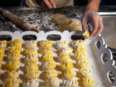 Kadın elleri mutfak masasında etli hamur köfteleri yontuyor. Bir dilim kıyma ve hamur dilimi ile yetişkin bir kadının ellerine yakın çekim. Ev yapımı etli börek yapma süreci. Ev yapımı.