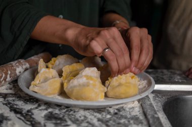 Kadın elleri mutfak masasında etli hamur köfteleri yontuyor. Bir dilim kıyma ve hamur dilimi ile yetişkin bir kadının ellerine yakın çekim. Ev yapımı etli börek yapma süreci. Ev yapımı.