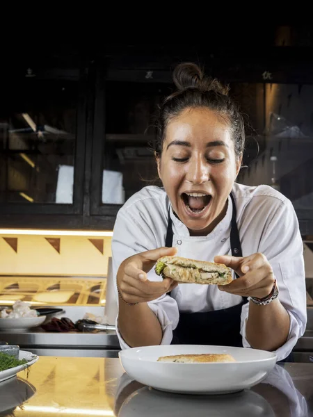 Happy woman chef eating sandwich. Close-up. Panini. Italian Cuisine.