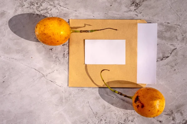 Mail envelopes with a blank sheet of paper for your signature with passion fruit on a gray background. Summer still life. Branding concept.