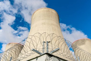 Dikenli tellerin arkasındaki nükleer santralin soğutma kulesi. İtiraz ediyorum..