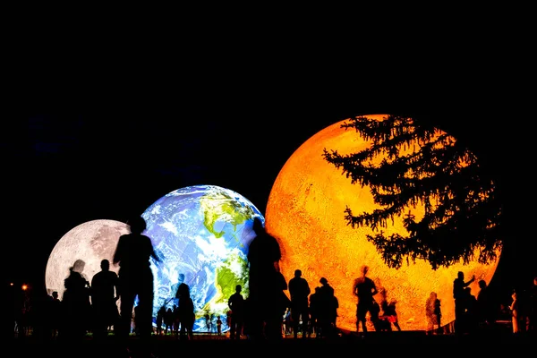 BRNO, República Checa - 14 de agosto. 2020 Modelo inflable gigante de los planetas Marte, Tierra y Luna por la noche con siluetas de personas. Investigación del sistema solar. —  Fotos de Stock