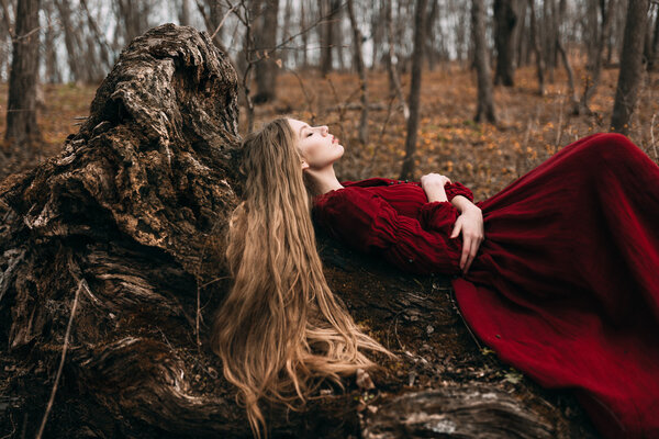 Young woman in red dress in the autumn forest