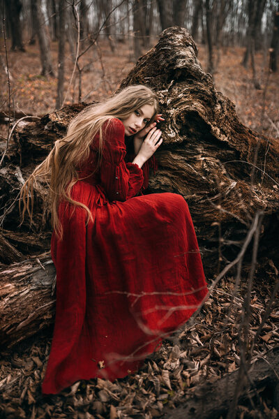 Young woman in red dress in the autumn forest