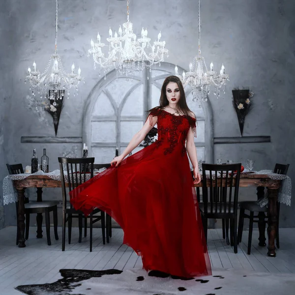 Bloodthirsty female vampire in red dress. Medieval interior — Stock Photo, Image