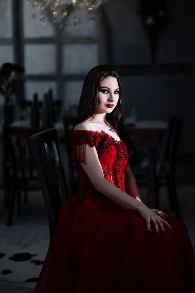 Blutrünstige weibliche Vampirin im roten Kleid. Mittelalterliches Interieur — Stockfoto