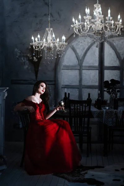 Blutrünstige weibliche Vampirin im roten Kleid. Mittelalterliches Interieur — Stockfoto