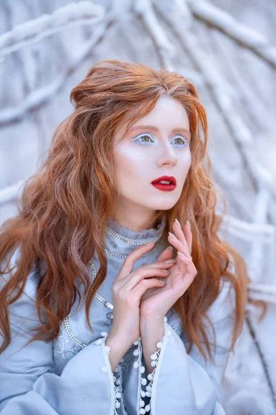 Young redhead woman, a princess, walks in a winter forest in a blue dress. — Stock Photo, Image