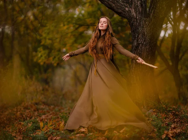 红头发女人穿着衣服走在梦幻童话森林里 图库图片