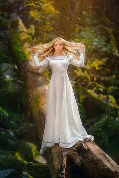 Красива молода жінка в білій сукні посеред лісу — стокове фото