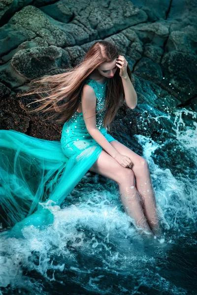 Woman posing on a beach with rocks — Stock Photo, Image