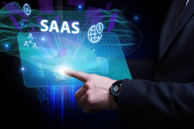 İş, Teknoloji, İnternet ve ağ konsepti. Genç işadamı geleceğin sanal ekranı üzerinde çalışıyor ve SAAS yazısını görüyor: