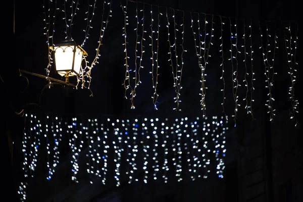 Sokak ışıkları ve karanlıkta yeni yıl ışığı. Geleneksel Noel ışıkları geceleri parlıyor. Yalnızlık kavramı. Kimse yok. Noel arifesi. LED aydınlatma. Enerji tasarrufu teknolojileri