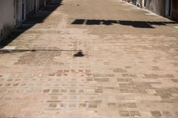 Concepto de cuarentena y encierro. Calle vacía con sombra de luz de calle y sábanas colgantes. No hay gente. Siesta en Sicilia. Pavimento de ladrillo. Ciudad muerta. Vista de calle pandémica. Imagen De Stock