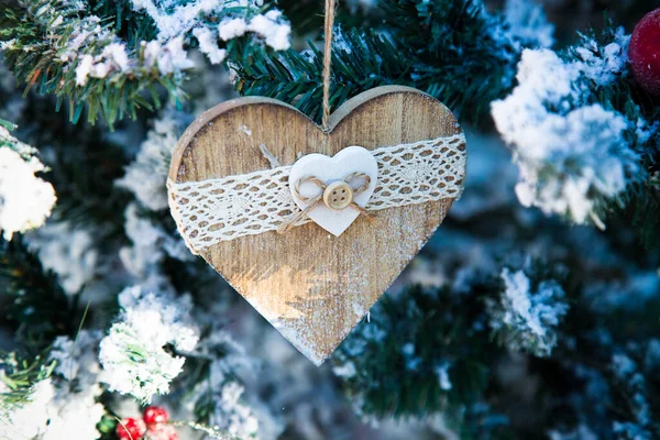 Decoração de madeira ano novo pendurado na árvore de Natal com neve. Coração com botão e risca. postal de inverno. Materiais naturais para o projeto home. Brinquedos de Natal e decoração artesanal. Parabéns. — Fotografia de Stock