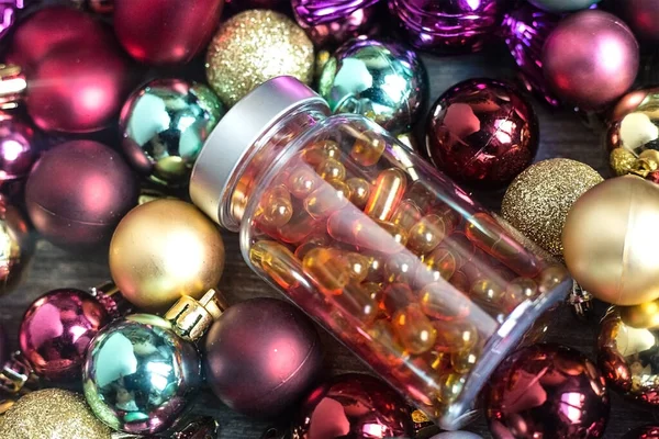 Plastic bottle with orange pills. Curcumine and vitamin D capsules on colourful Christmas balls. Coronavirus prevention. Healthy new year concept. Best present ever. Celebrating pandemic holidays. — Stock Photo, Image