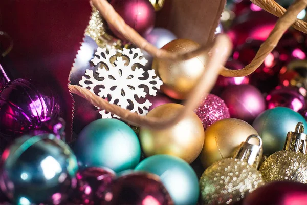 Floco de neve de madeira no saco vermelho presente em bolas de Natal multicoloridas. Brinquedos de árvore de ano novo coloridos espumantes. Composição de fundo de férias. Camada plana. Convite de fundo. Decorações de festa redonda — Fotografia de Stock