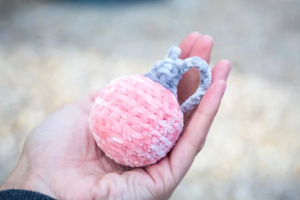 Woman holds in hand rose new year ball amigurumi. Knitted of plush yarn soft toy for Christmas decoration. Giving handmade Xmas presents. Making a gift. Handicrafts concept. Tender and softness