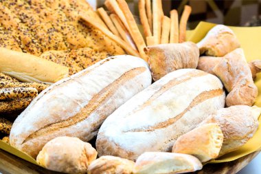 Diğer fırınla birlikte iki somun taze ekmek. Pazar pazarında çeşitli buğday fırını türleri. Beslenme sergisi. İtalyan geleneksel fırını. focaccia. Kartpostal kompozisyonu. Geçmişi. Gün ışığı