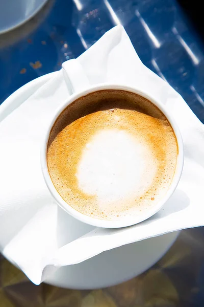 Vista superior para copo de porcelana branca de cappuccino italiano. Composição centrada. Café da manhã fresco com espuma de leite para o café da manhã. Dia ensolarado. Imagem de perto. — Fotografia de Stock